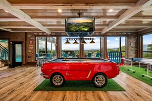 A pool table in a room with a red car, wooden ceiling, and large windows. - Welcome to Dancing Fox! Luxury 7BR, Indoor Pool, Fire Pit, Wow Views!!! (Sevierville)