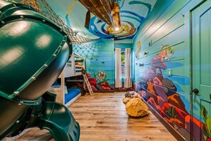 A room with a bunk bed, a slide, and a mural of fish.