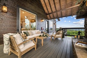 Une terrasse en bois avec un canapé, des chaises et une table, offrant une vue sur un paysage magnifique.