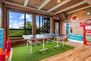Une table de ping-pong se trouve dans une pièce dont le sol est en bois et qui possède une grande fenêtre.