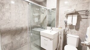 A modern bathroom with a glass-enclosed shower, a white sink, and a toilet.
