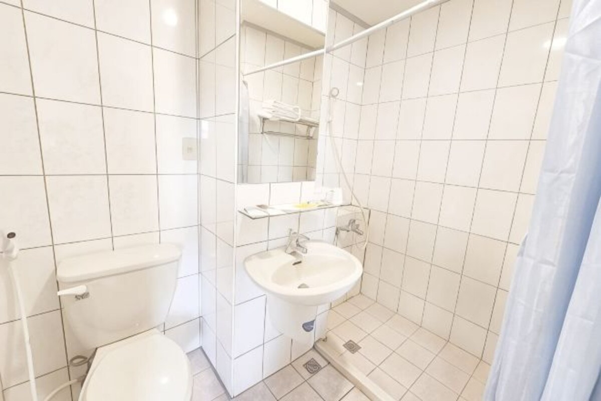 A bathroom with a toilet, sink, and shower area.
