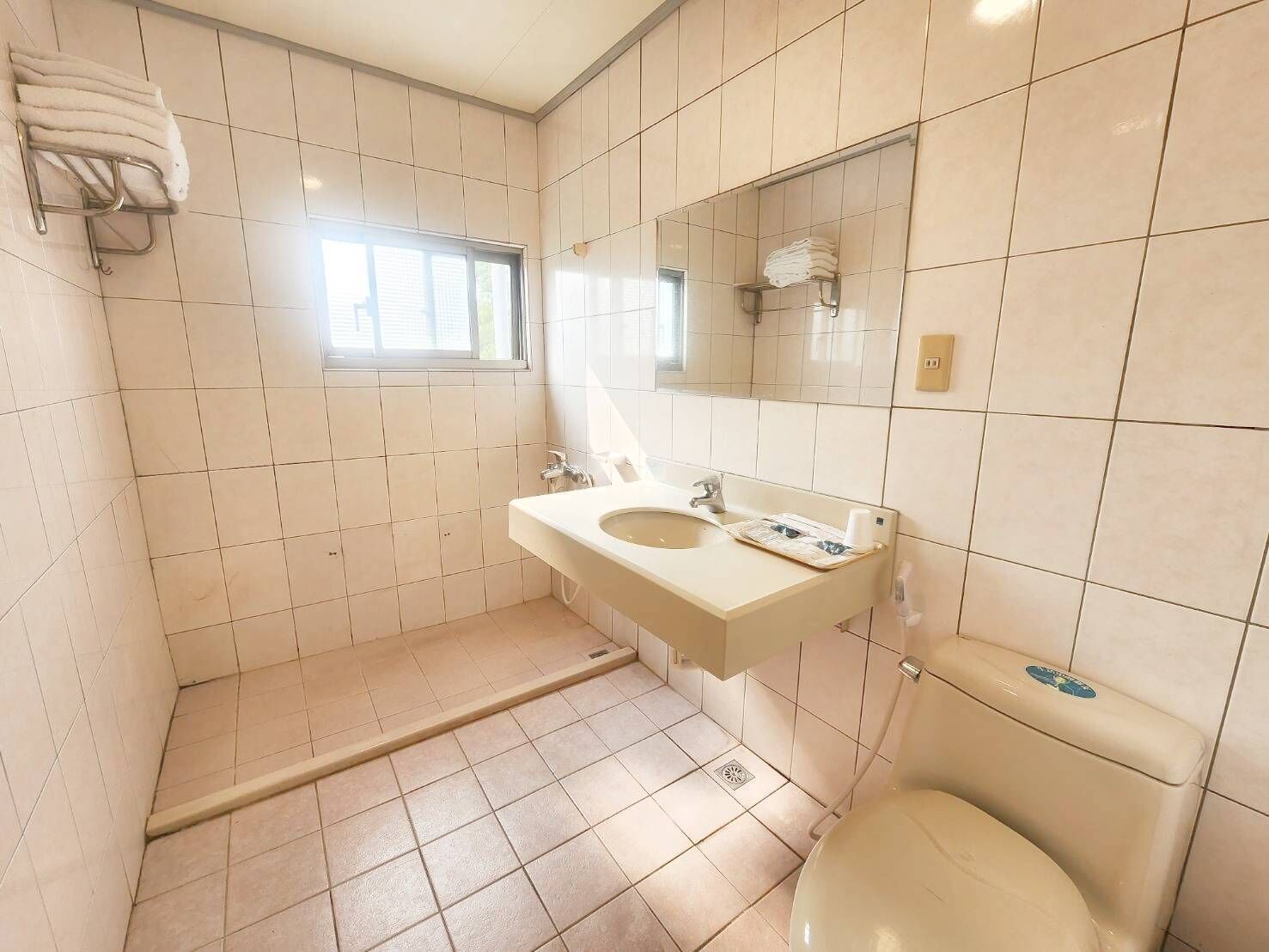 Ein Badezimmer mit Waschbecken, Spiegel, Toilette und Fenster.