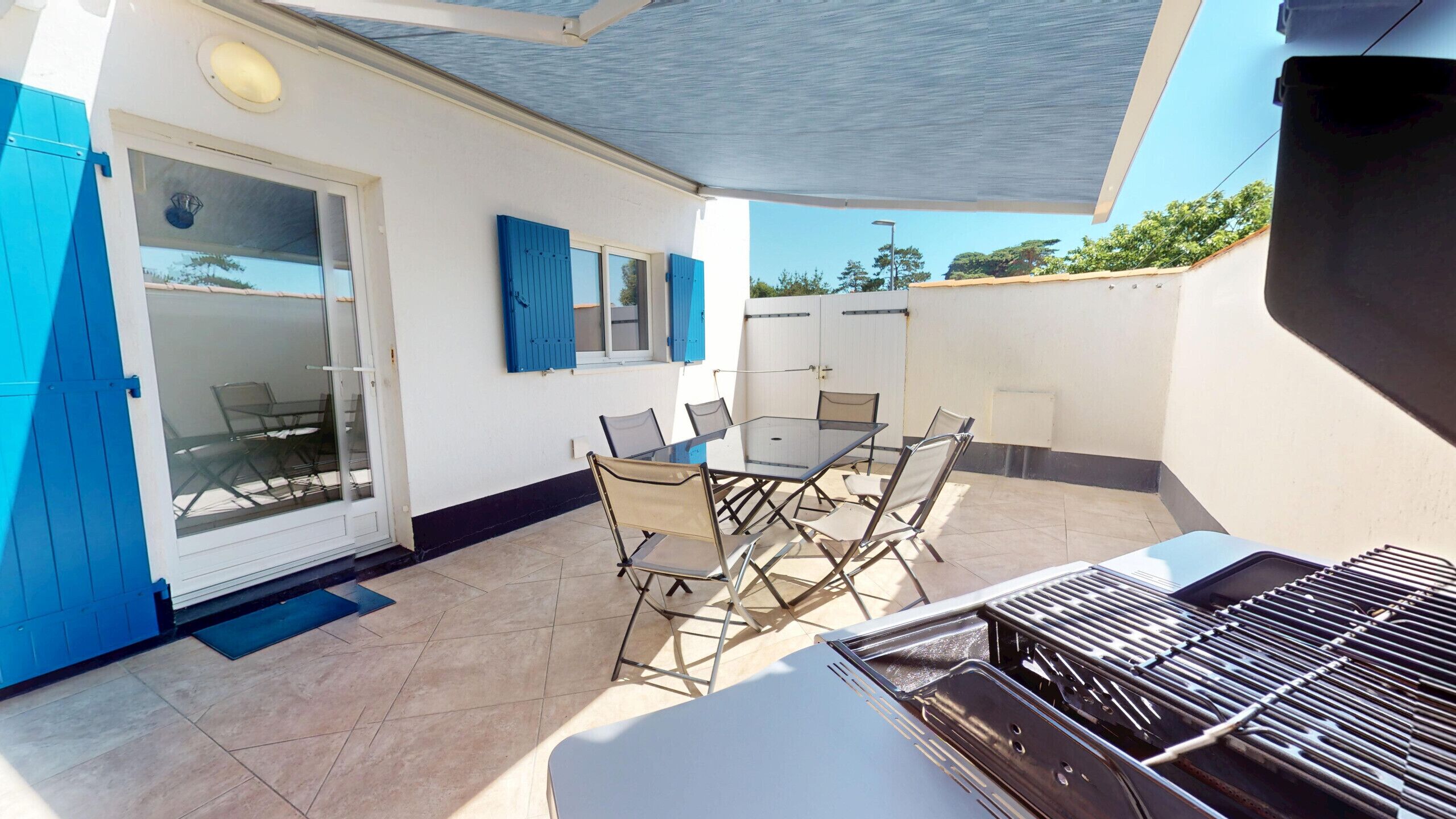 A patio with a table and chairs, a grill, and a sliding glass door.