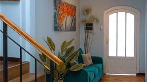 A staircase leading to a living area with a teal sofa, a painting, and a door with a window. - Casa del lado Santiago Providencia (Santiago)