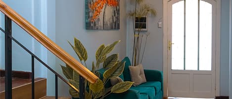 A staircase leading to a living area with a teal sofa, a painting, and a door with a window.