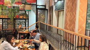A restaurant with wooden flooring, hanging plants, and a staircase with a wooden railing. - Casa del lado Santiago Providencia (Santiago)
