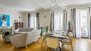 A spacious living room with a fireplace, modern furniture, and a dining area set for six.