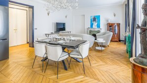 A dining area with a herringbone floor, a chandelier, and a dining table set for six.