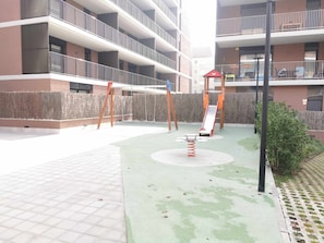 Children can play on the swing set, slide, and spring-mounted play structure in this outdoor play area.
