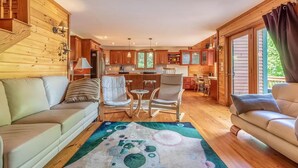 A cozy cabin interior with a living room, dining area, and kitchen.