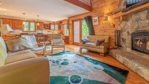 A cozy cabin interior with a living room, kitchen, and fireplace.