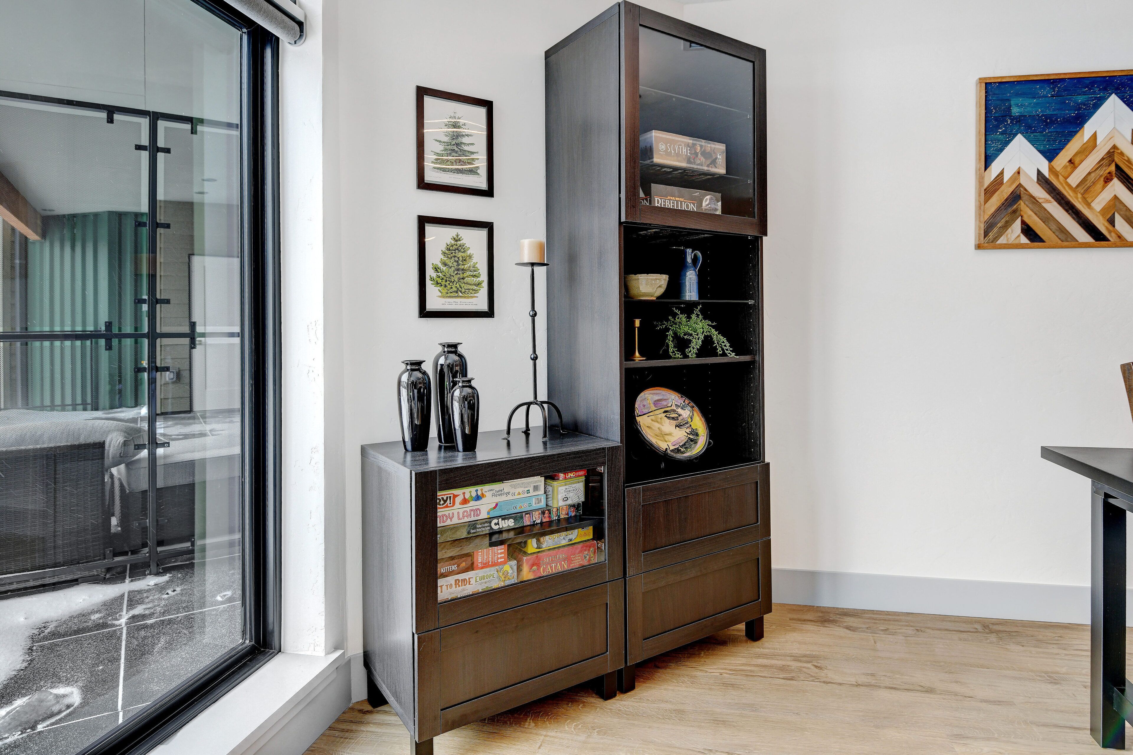 A modern living room with a dark wooden cabinet, books, and framed pictures on the wall.