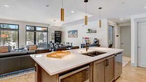 Eine moderne Küche mit einer großen Kochinsel, integriertem Backofen und einer Essecke mit Sofa und Tisch.