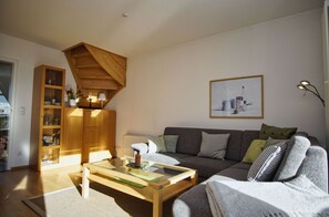 A living room with a wooden cabinet, a sofa, a coffee table, and a framed picture on the wall. - Hafenhäuser Breege Wohnung Nr. 03 Blinkfeuer - Hafenhäuser Breege (Breege)