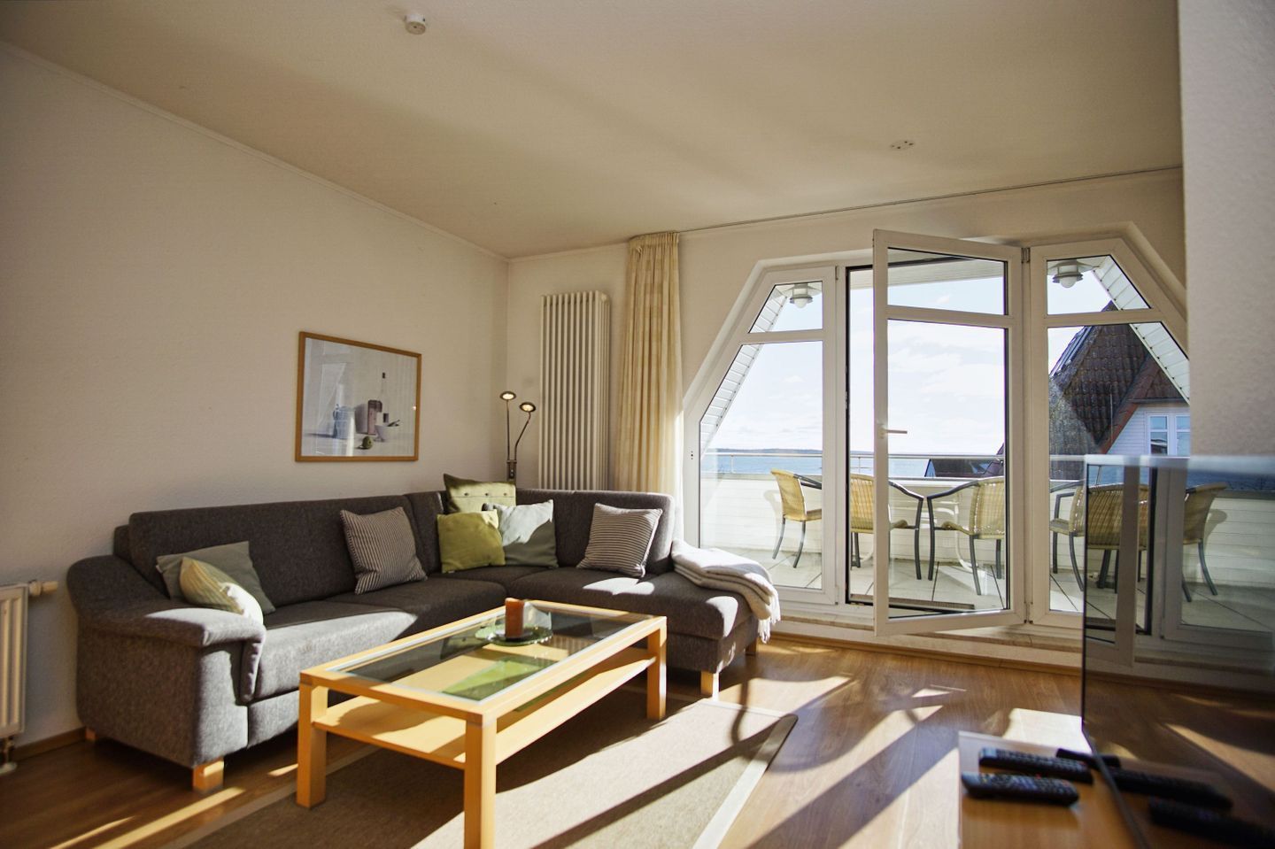 A living room with a sofa, a coffee table, and a view of the sea through large windows.