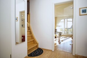 Una escalera conduce a un balcón con vistas, un piso de madera y una alfombra negra con diseños coloridos.