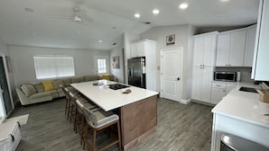 A modern kitchen with a central island, white cabinetry, and a stainless steel refrigerator. - Right off the main Weeki Wachee River! Beautiful updated home! (Spring Hill)