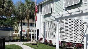 A white building with a lattice facade, a flagpole with an American flag, and a well-maintained lawn. - Right off the main Weeki Wachee River! Beautiful updated home! (Spring Hill)