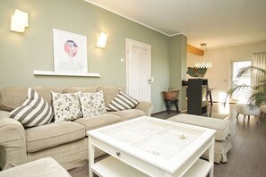 Un salón con un sofá beige, una mesa de centro blanca y un cuadro en la pared.