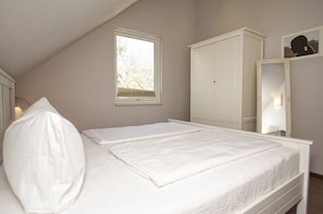 A bedroom with a bed, a wardrobe, a window, and a mirror.