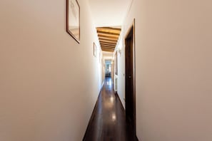 A hallway with wooden flooring, white walls, and framed pictures on the left. - San Giovanni House in Florence by Mmega (Firenze)