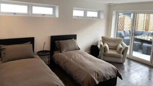 Una habitación de hotel moderna con dos camas, una zona de estar y vistas a través de un ventanal.