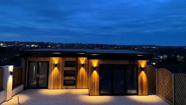 Un edificio moderno con fachada de madera, puertas de cristal amplias e iluminación exterior.