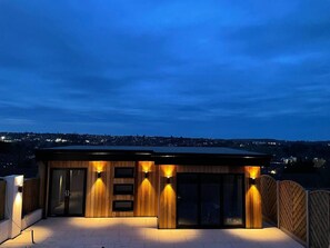 A modern building with a wooden facade, large glass doors, and exterior lighting. - The Hideaway Serviced Accommodation in Nottingham (Nottingham)