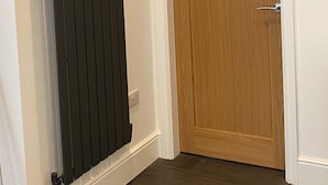 Una habitación con puerta de madera y radiador negro.