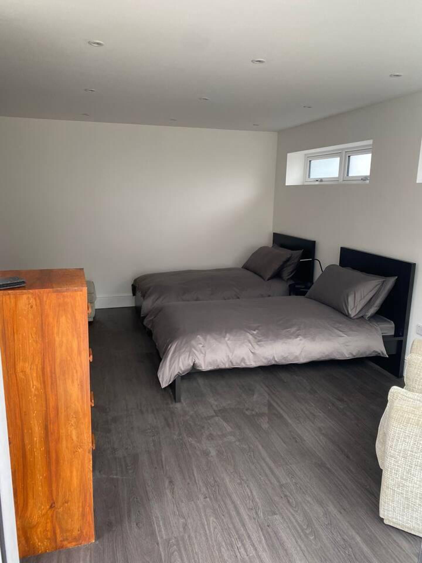 A bedroom with a bed, a wooden dresser, and a window.