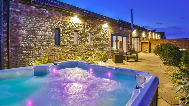 Ein Steinhaus mit Whirlpool und Sitzbereich im Freien.