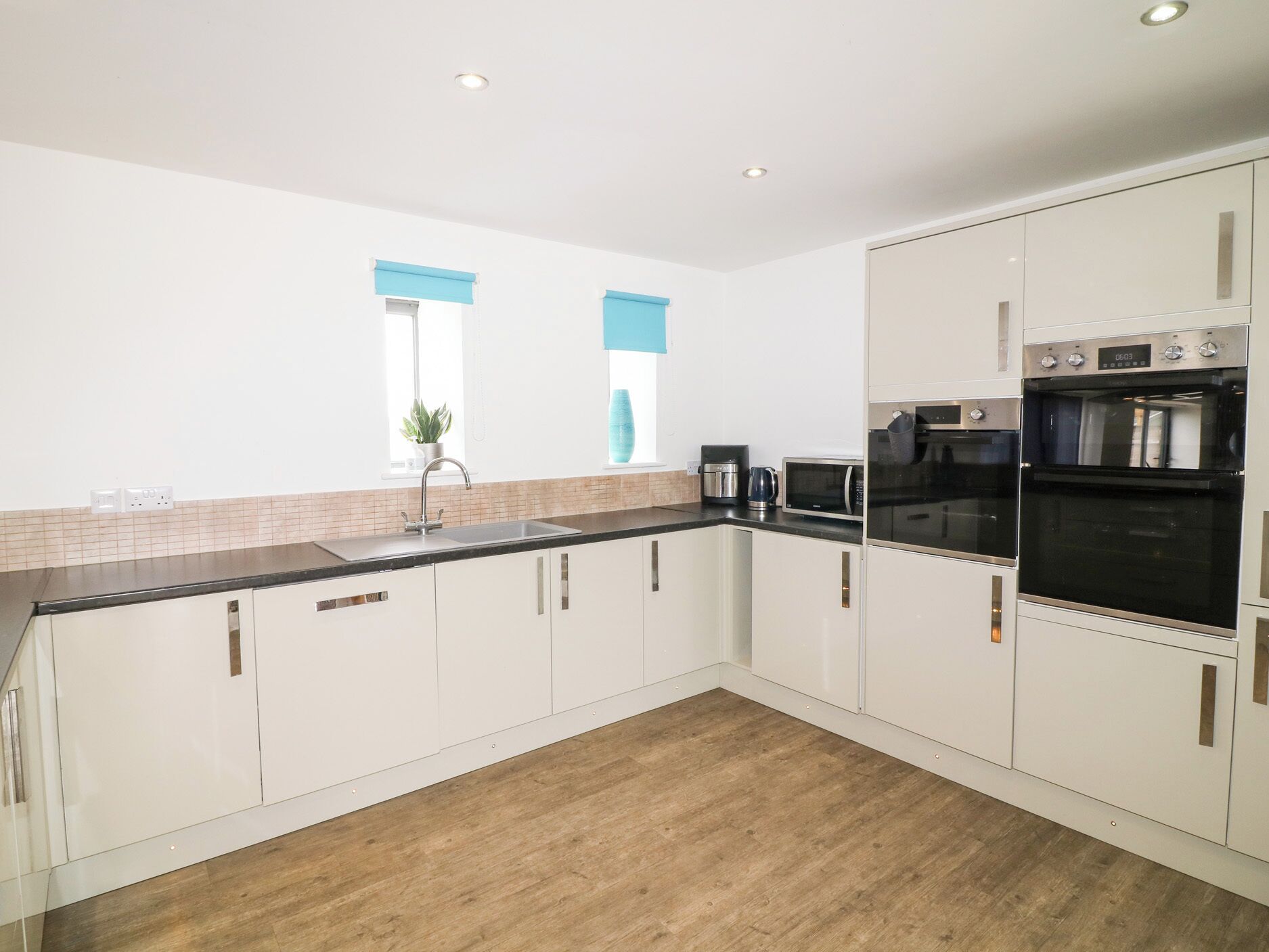A modern kitchen with white cabinets, a black countertop, and stainless steel appliances including a microwave and oven.