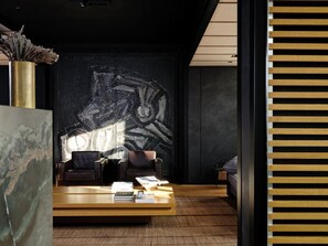 Un intérieur moderne avec un mur foncé, deux fauteuils en cuir, une table basse en bois et un vase décoratif.