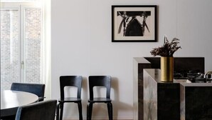 Une cuisine moderne avec un plan de travail en marbre, une chaise noire et une œuvre d’art encadrée accrochée au mur.