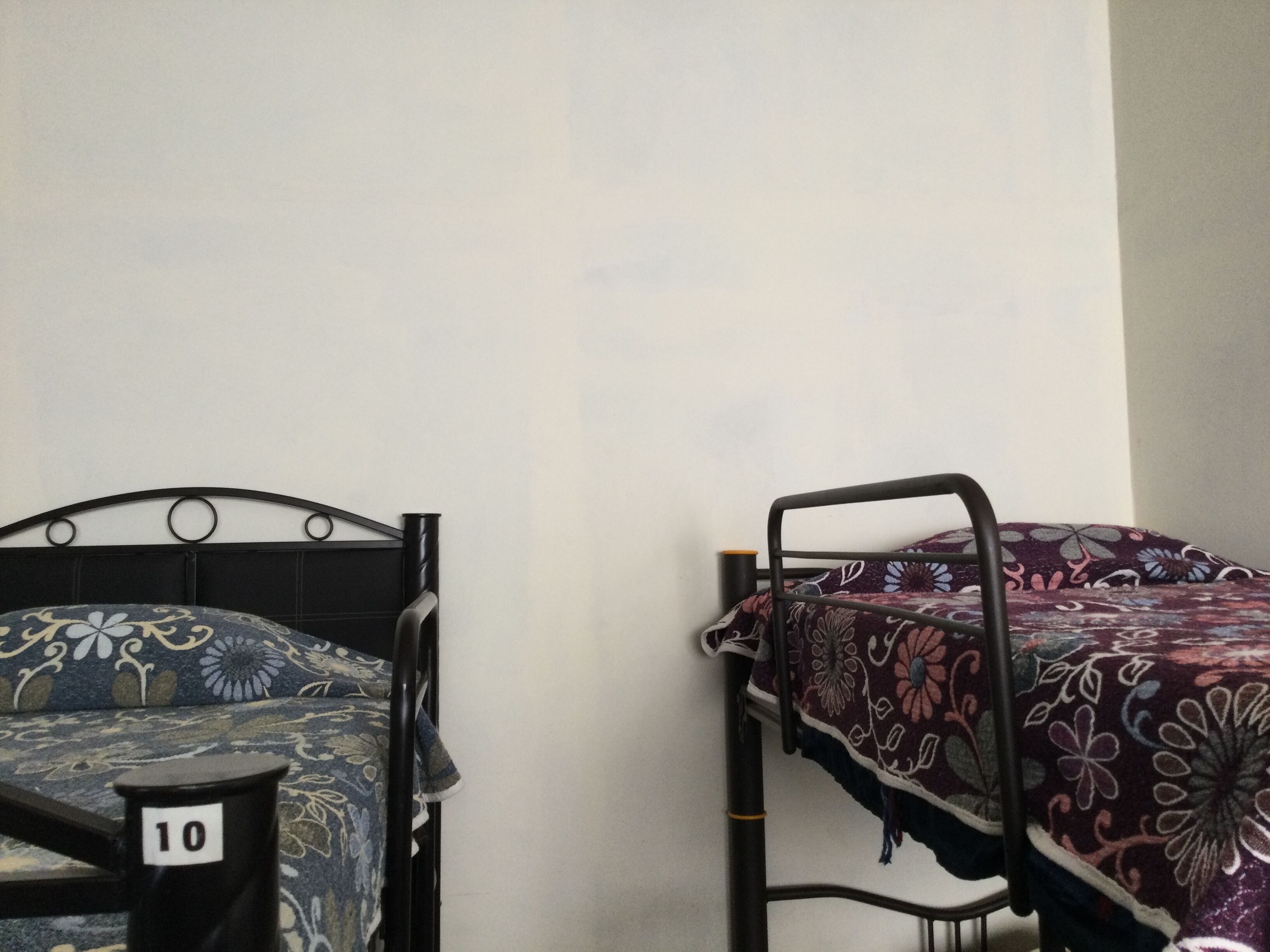 Two bunk beds with floral bedding, a wall-mounted number '10' sign, and a plain wall.