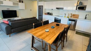 A modern kitchen with white cabinets, a wooden dining table, and a built-in oven. - Beautiful luxury 2-Bed Apartment in Pereybere (Grand Baie)