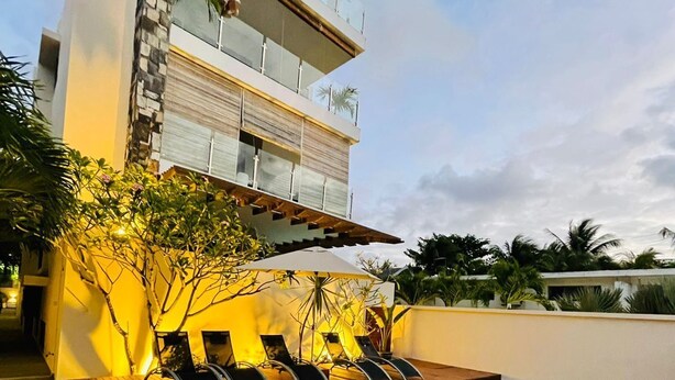 A modern pool area with a wooden deck, lounge chairs, and a clear pool. - Beautiful luxury 2-Bed Apartment in Pereybere (Grand Baie)