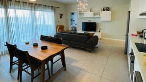A modern living room with a dining table, sofa, and TV. - Beautiful luxury 2-Bed Apartment in Pereybere (Grand Baie)