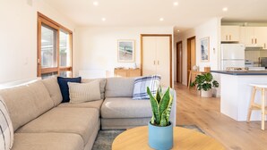 A modern living room with a beige sofa, a round coffee table, and a potted plant. - Torquay Hotel Motel (Torquay)