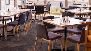A restaurant with tables and chairs, large windows, and hanging plants. - Torquay Hotel Motel (Torquay)