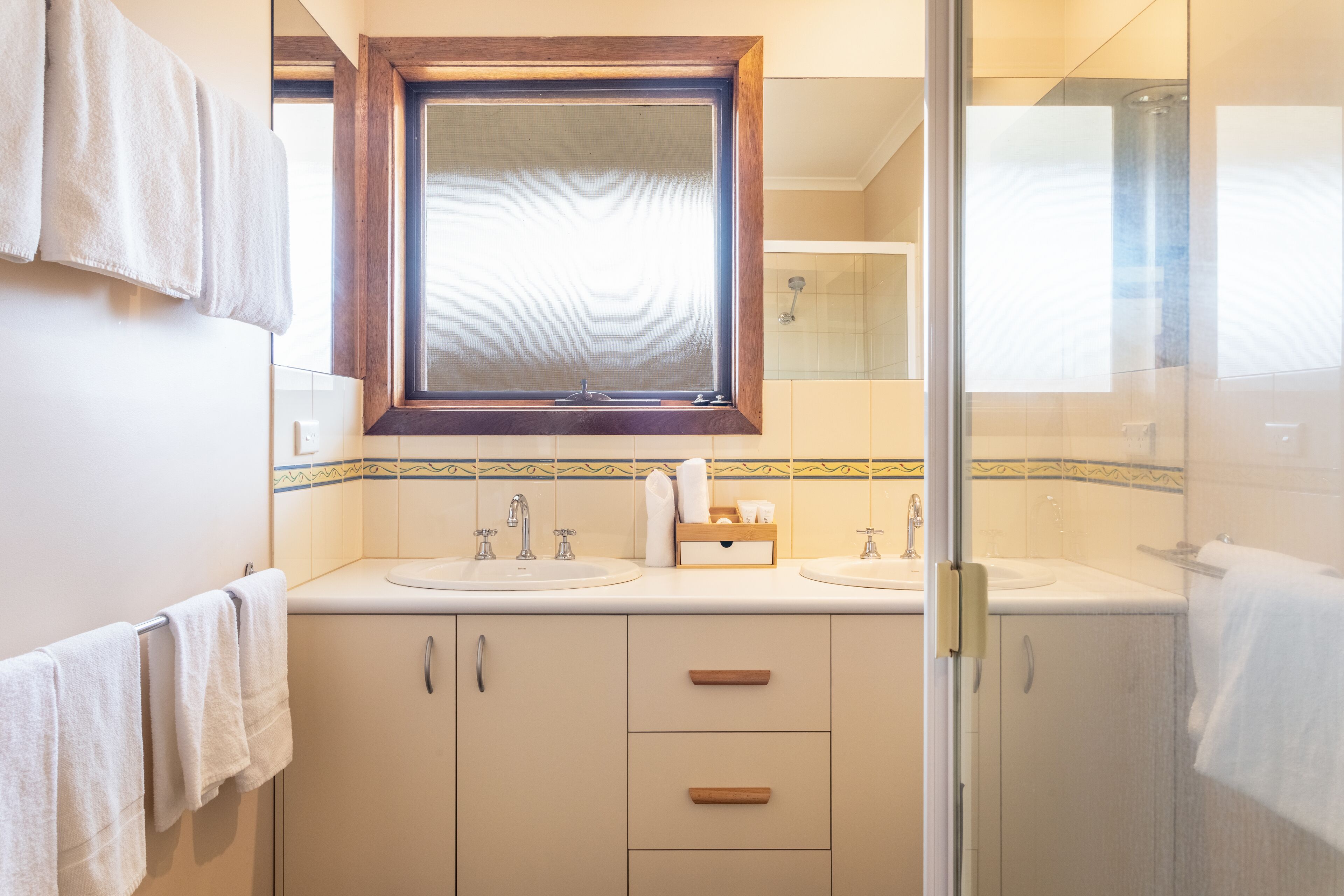 A bathroom with two sinks, a window, and a shower area.