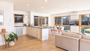 A modern kitchen with a central island, wooden flooring, and large windows. - Torquay Hotel Motel (Torquay)