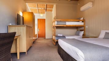 A room with bunk beds, a desk, and a television.