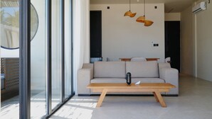 Een moderne woonkamer met een bank, een houten salontafel en hanglampen.