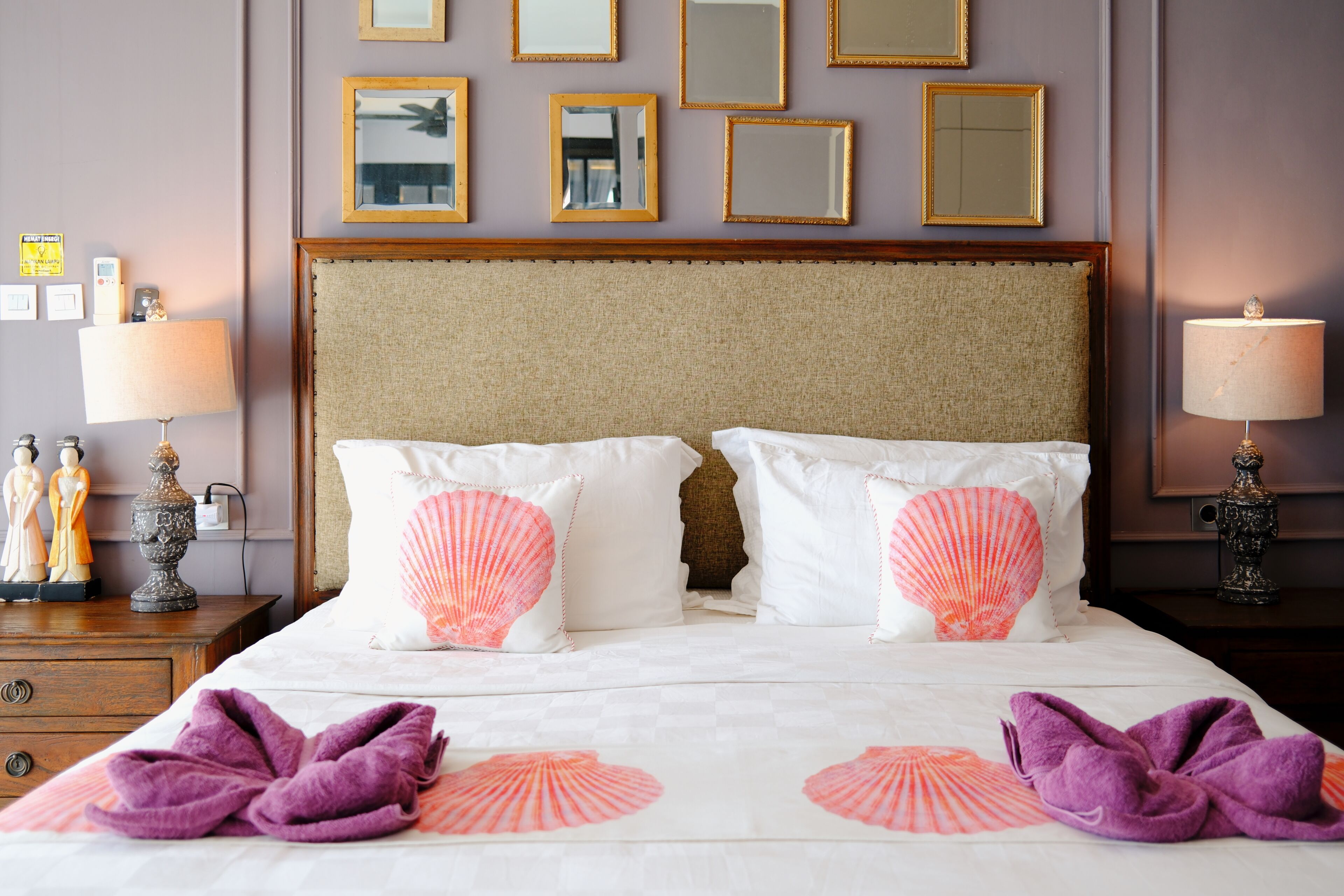 A hotel room with a large bed, two bedside lamps, a dresser, and a nightstand with a lamp.