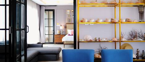 A modern living room with a sectional sofa, a blue chair, and a wooden dining table.