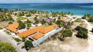 Luchtbeeld van een resort met meerdere gebouwen, palmbomen en een strand.