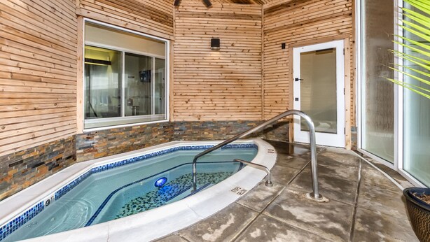 A wooden cabin with a glass door, a small pool, and a ceiling fan.