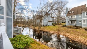A residential area with houses, a small pond, and a white fence.